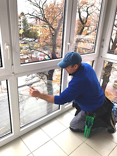 Fensterputzer kniet nieder und putzt ein Fenster