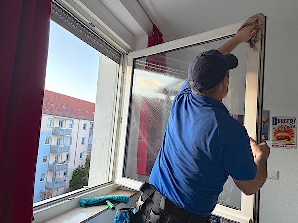 Ein-professioneller-Fensterputzer-wischt-in-einer-Privatwohnung-in-Nurnberg-im-Sommer-die-Fensterrahmen-mit-einem-sauberen-Tuch-ab